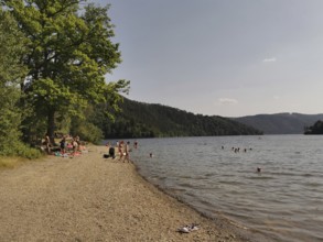Bathers relax on a pebble beach on a quiet lake, Hohenwarte Reservoir, Thuringian Forest nature