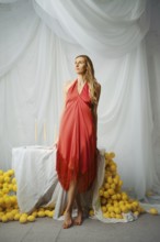 Barefoot woman poses near a table covered with a white cloth. Lemons surround the table as candles