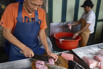 Bangkok, Thailand. March 10th 2025 A fishmonger chops tuna steaks in street market stall in