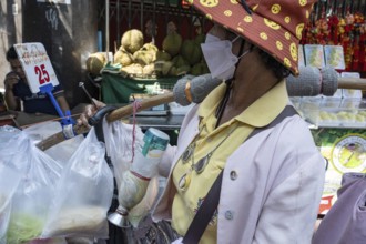 Bangkok, Thailand. March 25th 2025. A local women selling street food wearing a face mask to