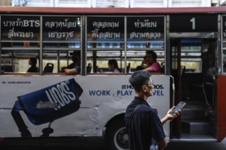 Bangkok, Thailand. February 18th 2025. A local man with a mobile phone waiting for a bus in
