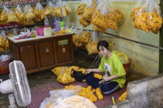 A Thai woman making traditional flower garlands at Pak Khlong Talat, a Bangkok flower market, Pak