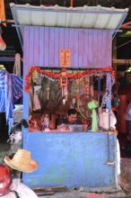Bangkok, Thailand. February 19th 2025. A worker sits inside a colourful booth at the Khlong Toei