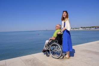 Senior in wheelchair looking at the sea, vacation with a handicap, Grado, Julian-Friuli, Adriatic