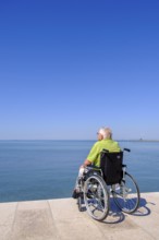 Senior in wheelchair looking at the sea, vacation with a handicap, Grado, Julian-Friuli, Adriatic