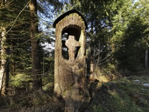 Wooden cross carved into a tree trunk in the forest in a cool atmosphere, hiking in the Franconian