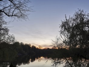 The sunset is reflected in a lake surrounded by trees, Franconian Forest nature park Park