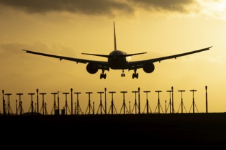 Boeing 777 commercial passenger jet aircraft in flight on approach to land over runway lights