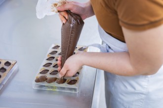 Hand fills chocolate in chocolate form, craftsmanship and precision, vegan chocolates production,