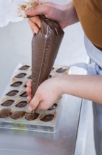Hand fills chocolate in chocolate form, careful preparation, vegan chocolates production,