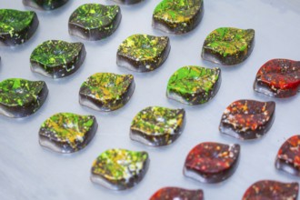 Colourful chocolates shaped like autumn leaves, arranged on a platter, vegan chocolates production,