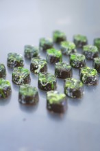 Fully decorated chocolates with green decoration on a surface, vegan chocolates production,