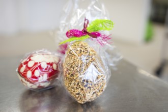 Gift wrapping of Easter eggs made from sweets and nuts in transparent foil, Easter production of