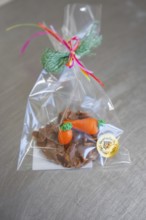 Chocolate snack with carrot decoration in a transparent bag, decorated with green gift ribbon,