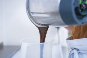 Liquid chocolate is poured from a mixer, Vegan Tarts Production, Haselstaller Hof, Gechingen,