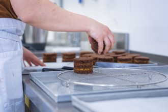 Person places cookies on a grid in the kitchen, vegan cake production, Haselstaller Hof, Gechingen,