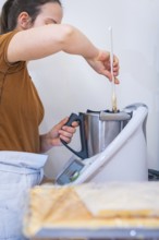 Woman stirring ingredients in a mixer in the kitchen, vegan cake production, Haselstaller Hof,