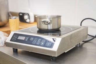 Stainless steel pot on an inductive hotplate in a modern kitchen environment, vegan cake