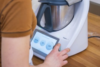 Person operating the display of a modern food processor, Vegan Tart Production, Haselstaller Hof,