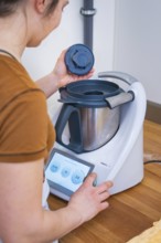 Person places the lid on a food processor during preparation, vegan cake production, Haselstaller