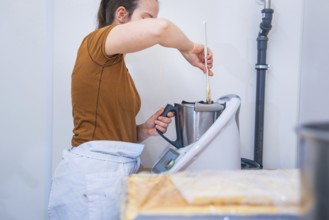 Woman mixes ingredients in a mixer in the kitchen, vegan cake production, Haselstaller Hof,