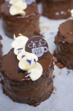 A chocolate covered cake decorated with white chocolate and logo, Vegan Tart Production,
