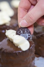 A small round dessert decorated with white chocolate and café emblem, vegan cake production,