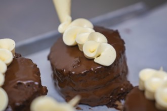 Chocolate cake is decorated with elegant cream decoration from a piping bag, vegan cake production,