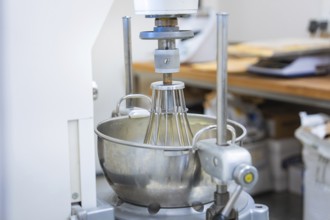 An industrial kitchen mixer with a large metal mixing container in a bakery, vegan cake production,