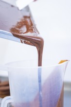 Liquid chocolate is poured from a rectangular container into a plastic container, Vegan Tart