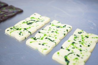 White chocolate bars with green patterns lying side by side on a table, vegan chocolate production,