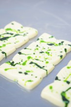 White chocolate bars with green splashes and patterns on a table, vegan chocolate production,