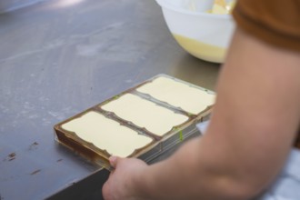 Hands holding chocolate molds in a work area on a table, Vegan Chocolate Production, Haselstaller