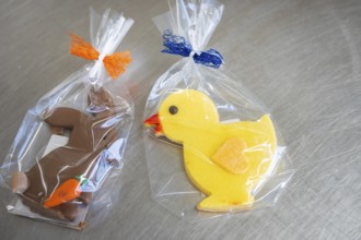 Yellow duck cookie and brown rabbit cookie, both wrapped in foil with colorful ribbons, Easter