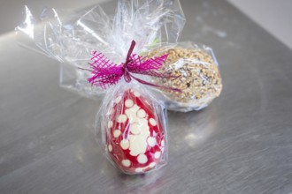 Two wrapped Easter eggs, one dotted in red and white with a bow, another covered with nuts, Easter