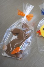 Brown chocolate rabbit cookie with carrot, wrapped in transparent film with orange ribbon, Easter