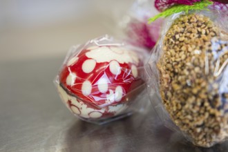 Chocolate Easter egg with nuts and a red and white egg, both packed in plastic, Easter production