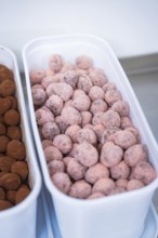 A container full of pink chocolates in a kitchen, chocolate quail eggs, Easter production,