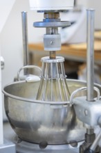 Large mixing machine with metal bowl in a professional kitchen, chocolate quail eggs, Easter