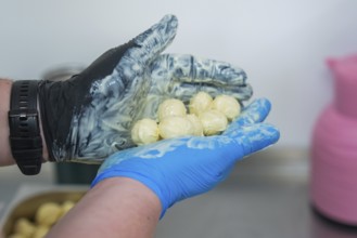 A hand in gloves holds chocolates over a bowl with pink and blue decoration, chocolate quail eggs,