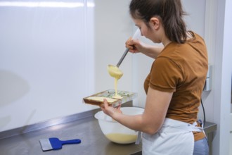 A woman pours chocolate mix into a mold in a kitchen, chocolate quail eggs, Easter production,