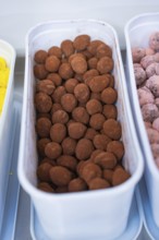 Container full of brown chocolate chocolates in a kitchen, chocolate quail eggs, Easter production,