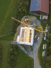 Construction site with crane and solar panel on a large building from a bird's eye view, timber