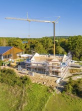 Building construction with scaffolding and crane in green surroundings, timber house construction,