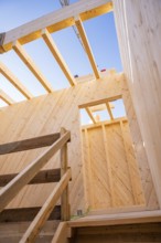 Looking up through the wooden structure of a building on blue sky, timber house construction,