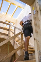 Workers on wooden stairs in a building under construction under blue sky, timber house
