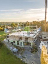 Building in nature with scaffolding and crane at sunset, timber house construction, Gechingen,