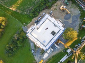 Aerial view of a construction site with building foundation and crane in a green landscape, timber