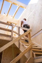 Workers climbing a wooden staircase in a partially converted building, timber house construction,