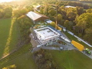 Construction site with a concrete foundation in a rural area, surrounded by green spaces, timber